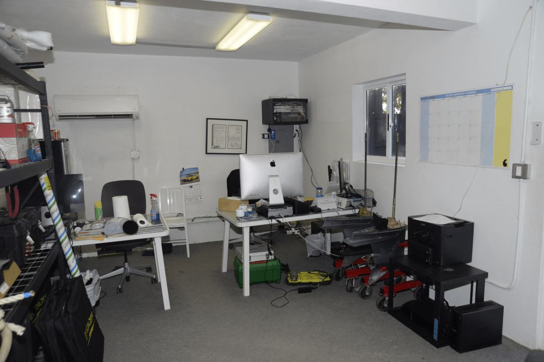 An office workspace with desks, computers, and a calendar on the wall